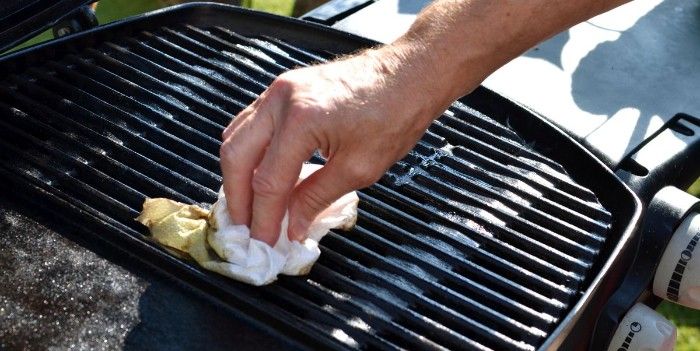 making sure a grill is seasoned by wipping with and rag covered in oil